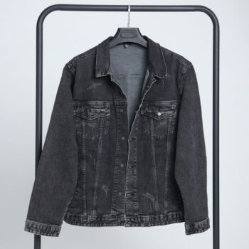 alt=“جکت جین زغالی ساده DO57، نما از روبرو با دکمههای فلزی نقرهای و طراحی باکسی یونیسکس روی زمینه سفید.”