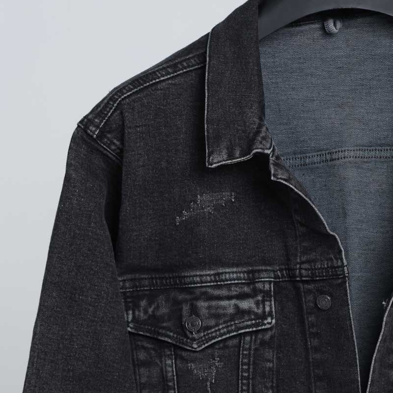 alt=“نمای نزدیک از پارچه جین زغالی و دکمه فلزی براق جکت DO57با کیفیت دوخت صنعتی و بافت سنگشوی طبیعی.”