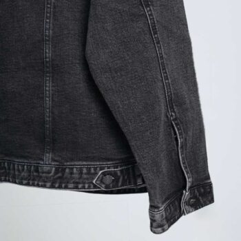 alt=“جکت جین زغالی ساده کد DO57آویزان بر چوب لباسی، رنگ زغالی سنگشوی، دکمه فلزی و دوخت منظم.”