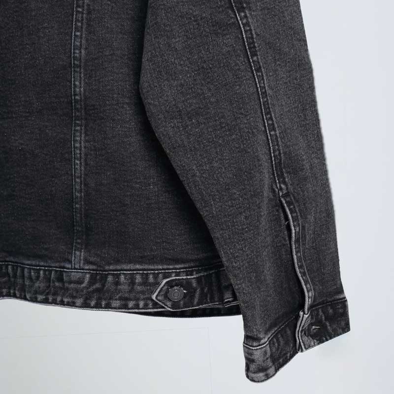 alt=“جکت جین زغالی ساده کد DO57آویزان بر چوب لباسی، رنگ زغالی سنگشوی، دکمه فلزی و دوخت منظم.”